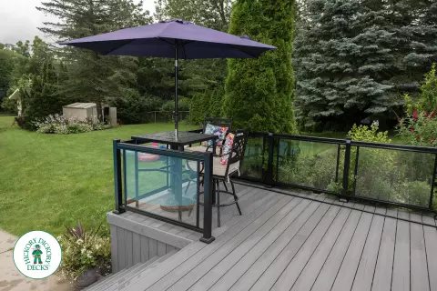 Large grey clubhouse deck with multi levels, lights in the steps, and glass railings.