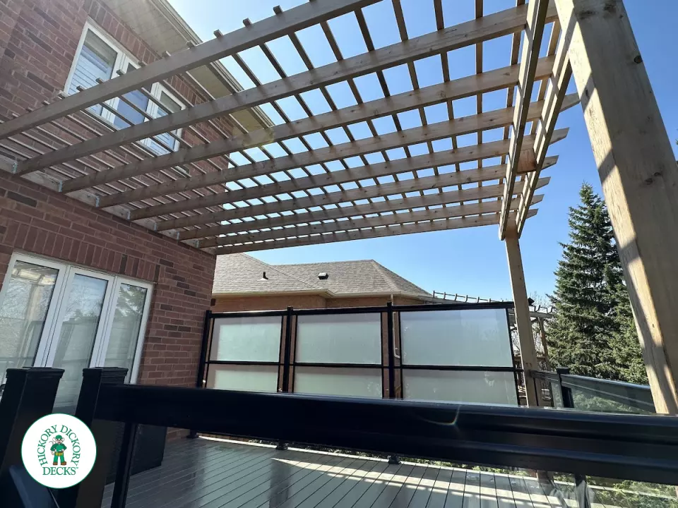Large high deck with pergola, glass railing and frosted glass privacy screen.