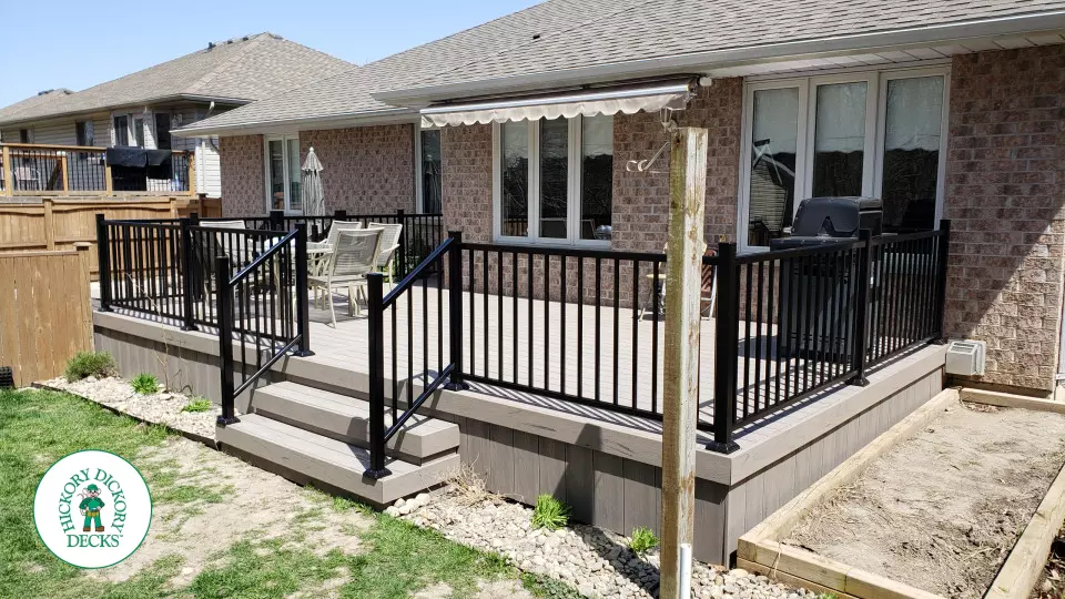 TruNorth composite deck in light grey color with three steps and black aluminum railing.