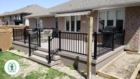 TruNorth composite deck in light grey color with three steps and black aluminum railing.