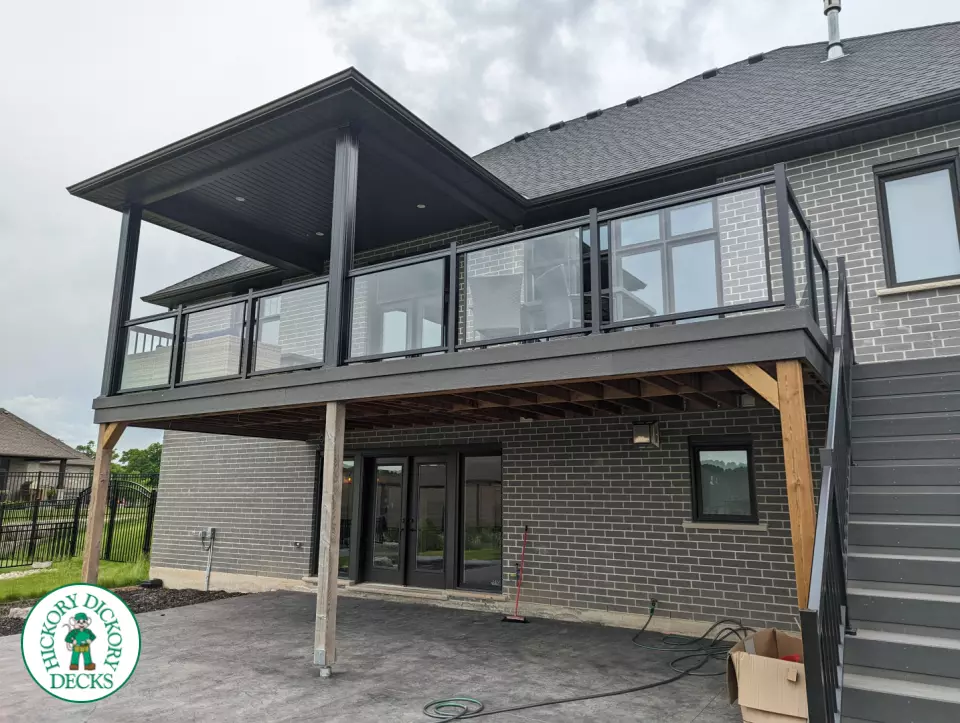Large high grey trunorth deck with glass railings, and a custom roof structure.