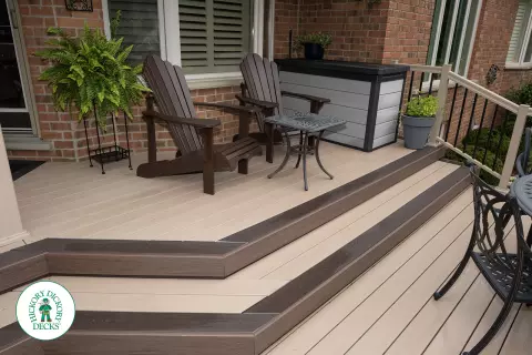 221 square foot light brown deck with dark brown border. This deck has curved steps and glass railings.