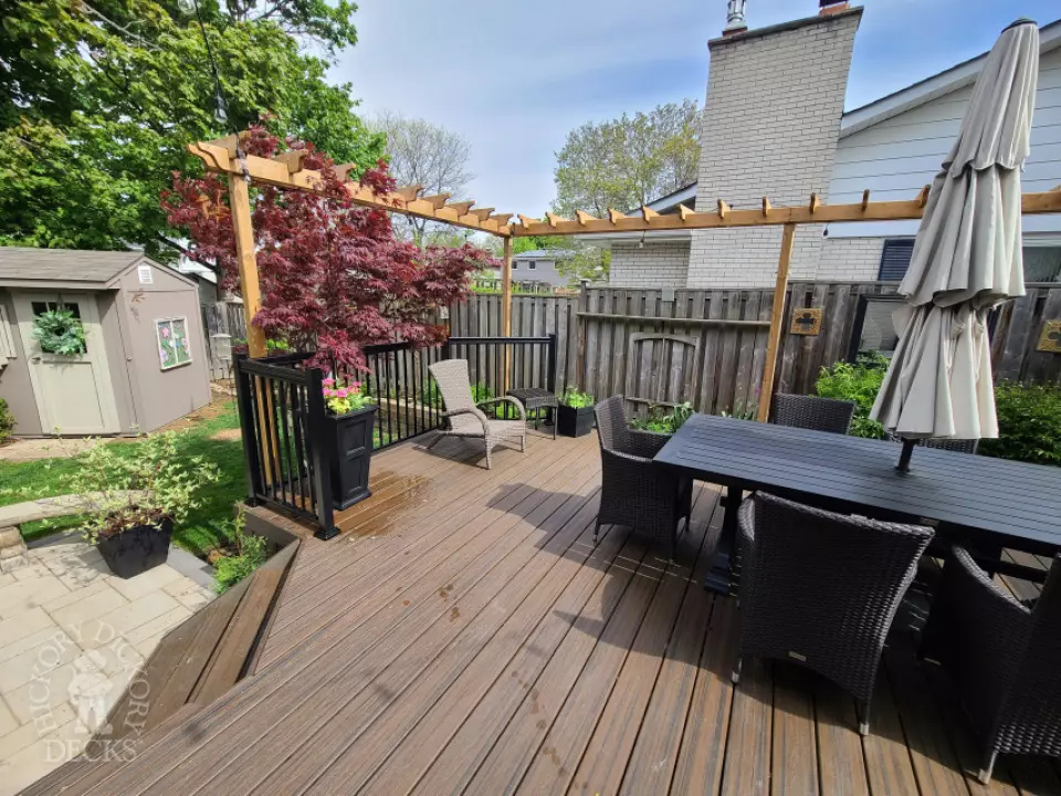 Large brown composite deck with pergola and unique stairs.