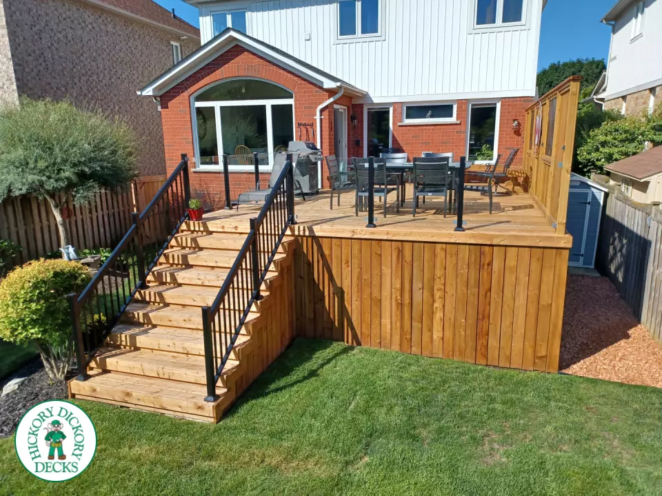 Mid rise pressure treated deck with glass railings, steps, and a custom cedar privacy screen