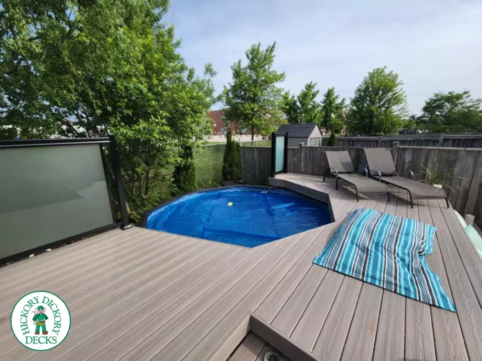 Grey Fiberon deck surrounding above ground pool with smoked glass railing.