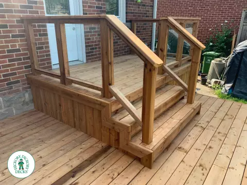 Small pressure treated deck with glass rail and a gate in skirt for storage.