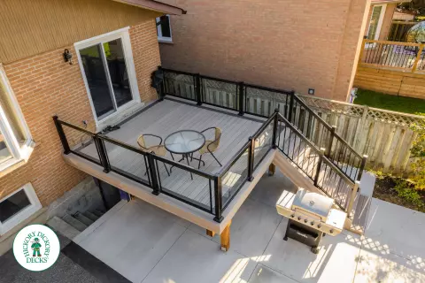 Mid rise grey composite deck with glass railings and a dark grey border.