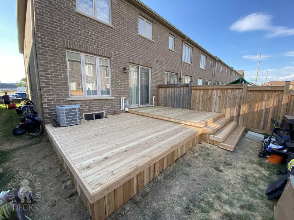 Cedar deck with no railings and four steps leading to backyard