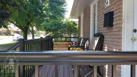Small brown fiberon porch with black aluminum railing.
