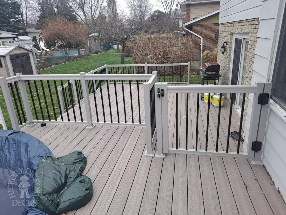 Two level grey Fiberon deck with beige picket aluminum railing and the top level surrounding an above ground pool.