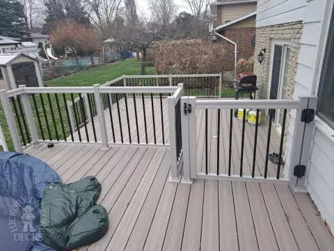 Two level grey Fiberon deck with beige picket aluminum railing and the top level surrounding an above ground pool.