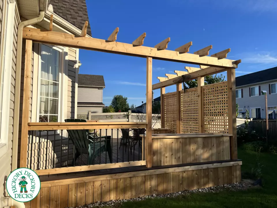 Mid size clubhouse deck in brown with cedar skirt, benches, planters, and a pergola.