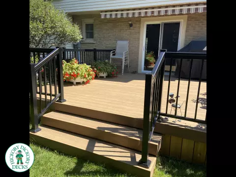 3 steps leading to small brown clubhouse deck with black aluminum railing.