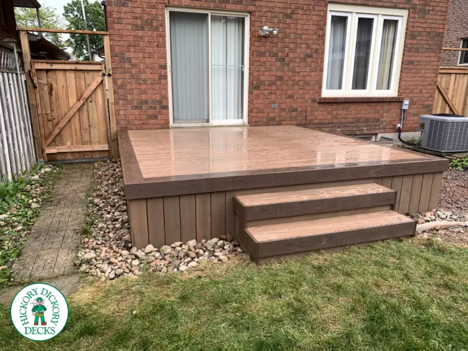 Small brown composite deck with three steps leading to yard.