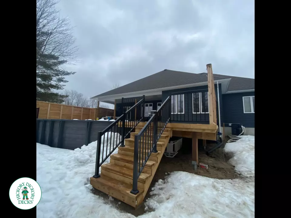 Cedar deck with stairs leading to walk out deck with aluminum railing and a cedar privacy screen.