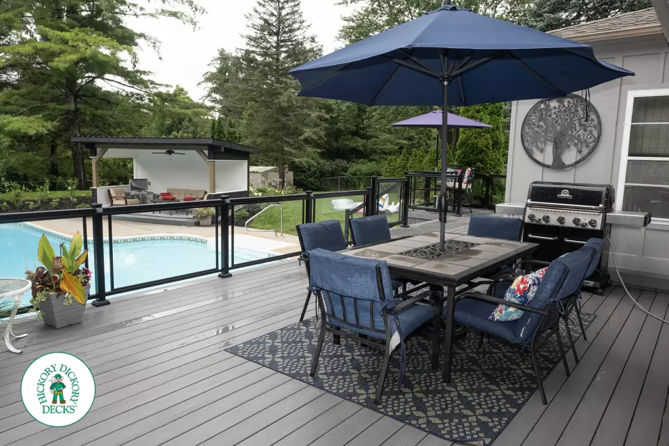 Large grey clubhouse deck with multi levels, lights in the steps, and glass railings.