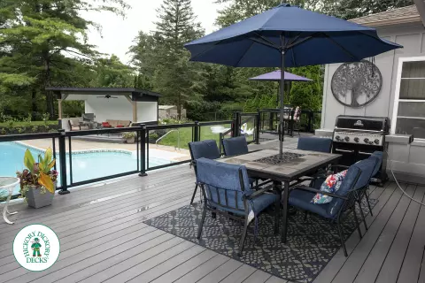 Large grey clubhouse deck with multi levels, lights in the steps, and glass railings.