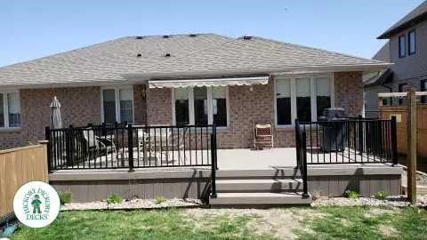 TruNorth composite deck in light grey color with three steps and black aluminum railing.