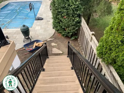 High composite deck with stairs that lead to pool and glass style railings.