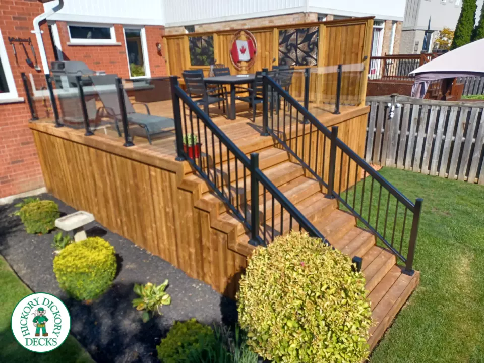 Mid rise pressure treated deck with glass railings, steps, and a custom cedar privacy screen