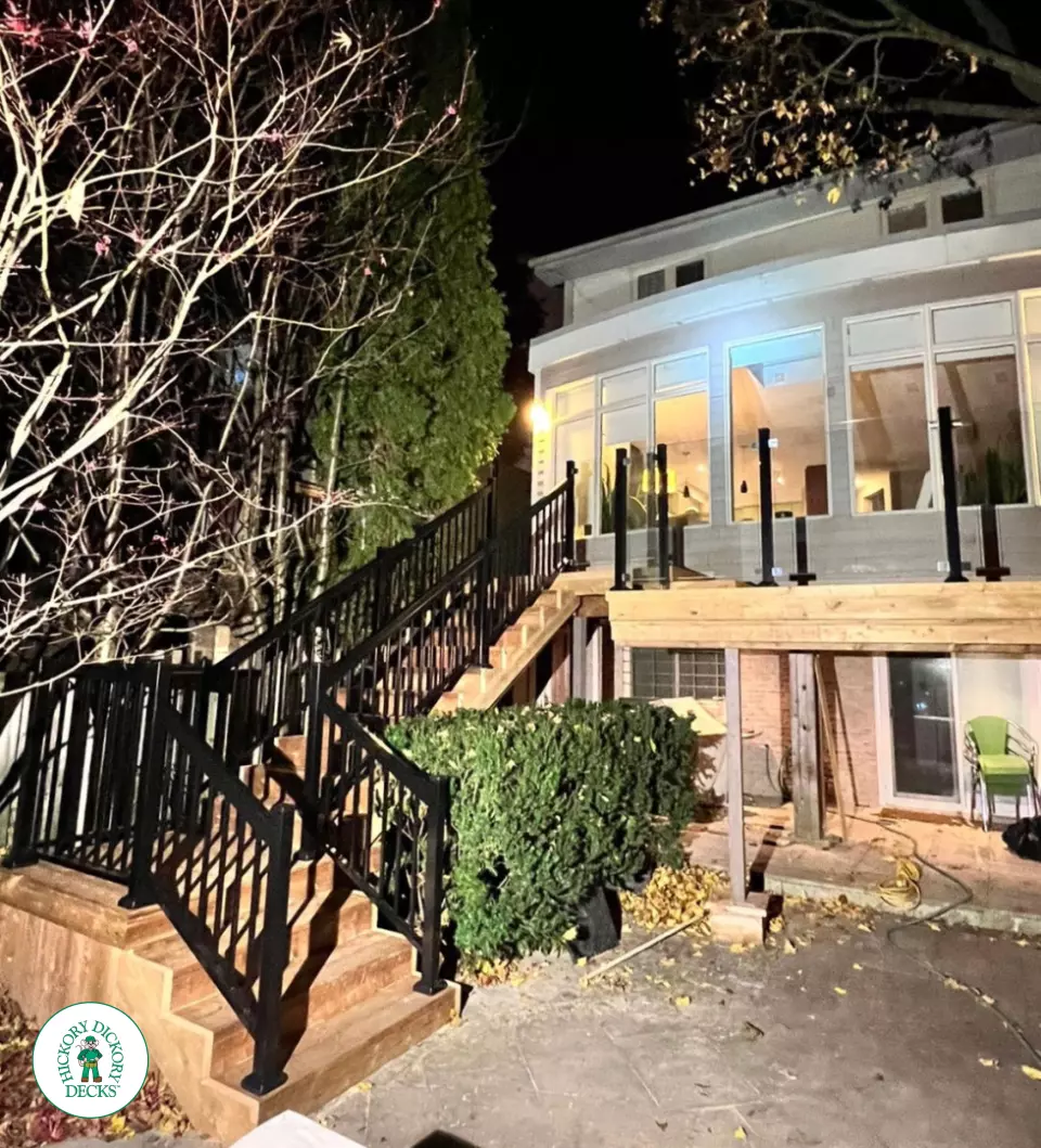 High cedar deck with glass railings and a lighting system around the deck.