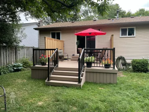 Small CLubhouse deck with four steps leading to backyard, black aluminum railing, and a cedar privacy screen.