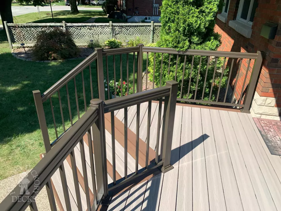 Grey front porch with brown trim and brown aluminum railing.