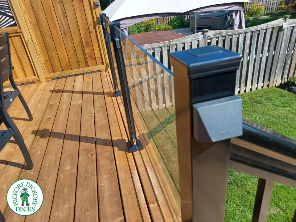Mid rise pressure treated deck with glass railings, steps, and a custom cedar privacy screen