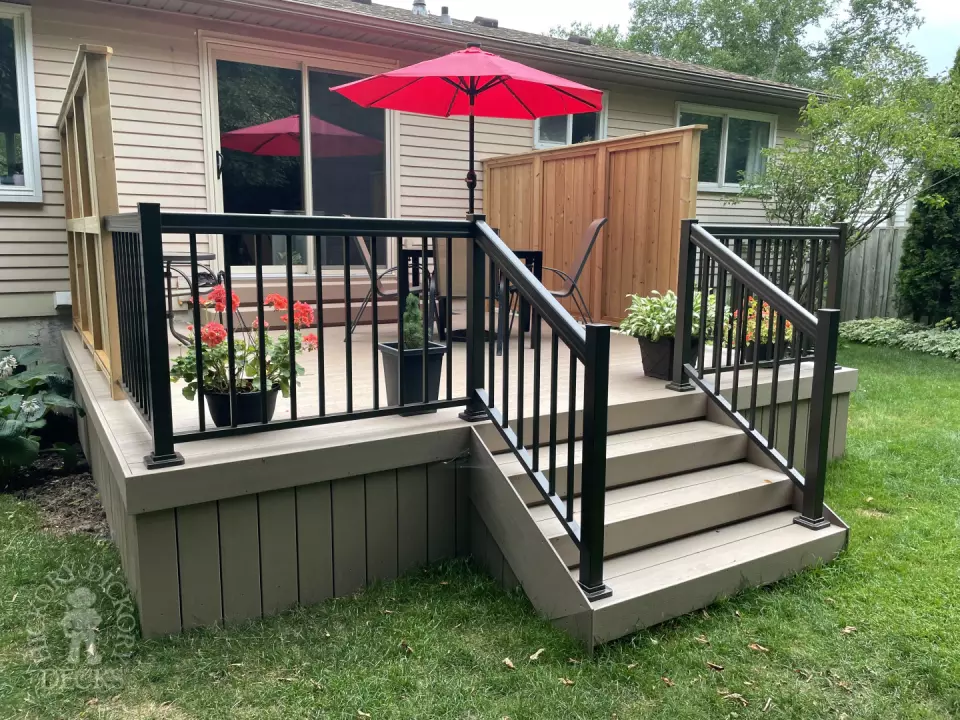 Small CLubhouse deck with four steps leading to backyard, black aluminum railing, and a cedar privacy screen.