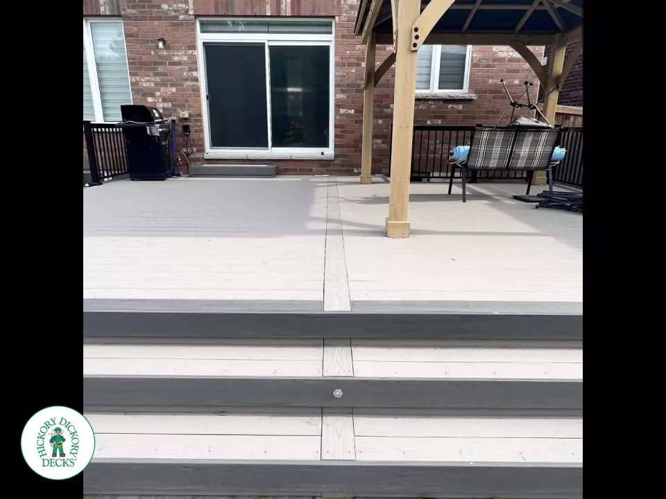 3 steps leading to a large Azek deck with lighting in the steps, and black aluminum railings.