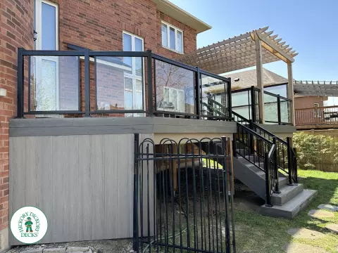 Large high deck with pergola, glass railing and frosted glass privacy screen.
