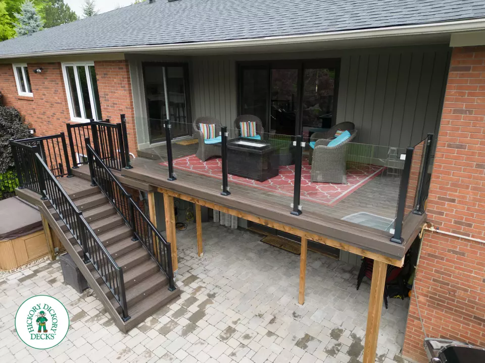 High brown deck with glass railings and lights in the stairs.
