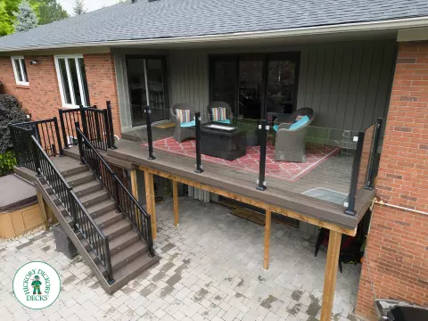 High brown deck with glass railings and lights in the stairs.