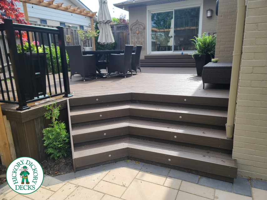 Large brown composite deck with pergola and unique stairs.
