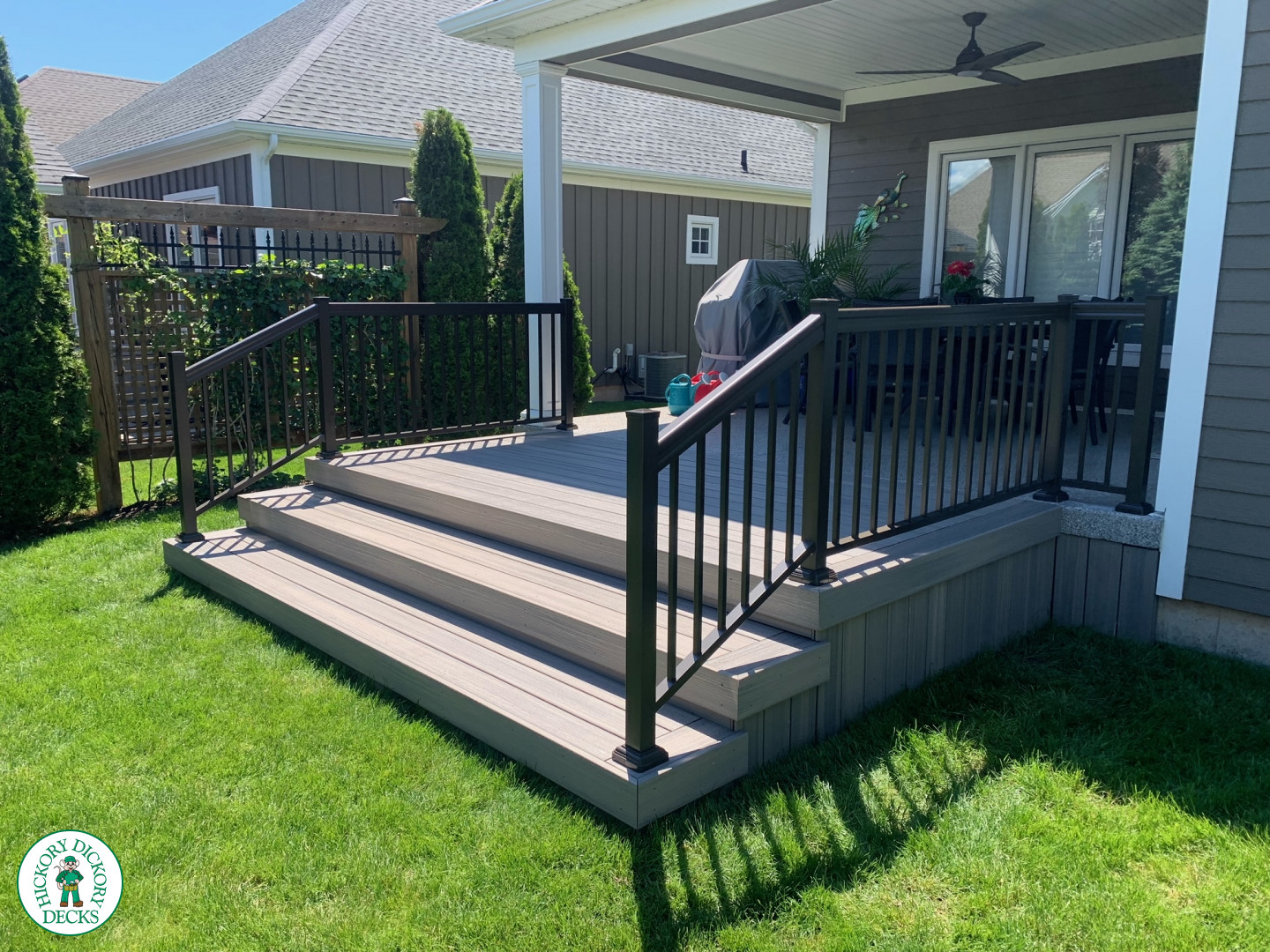 Small covered grey composite porch with aluminum railing.