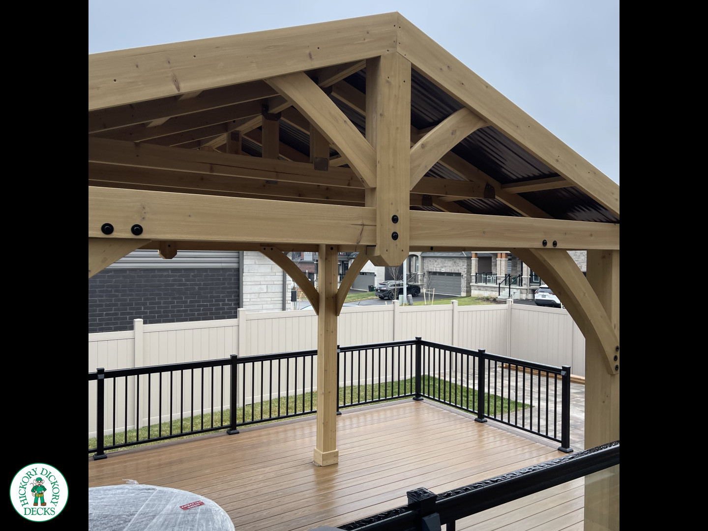 Brown composite deck with a roof structure, glass railings, access to the hot tub, and frosted glass privacy screens.