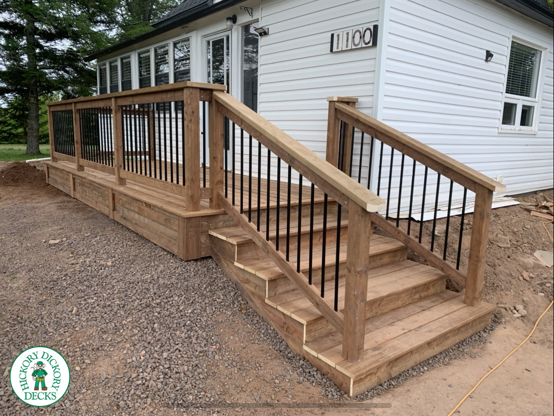 Pressure treated front porch with cedar railings and steps leading to front yard.