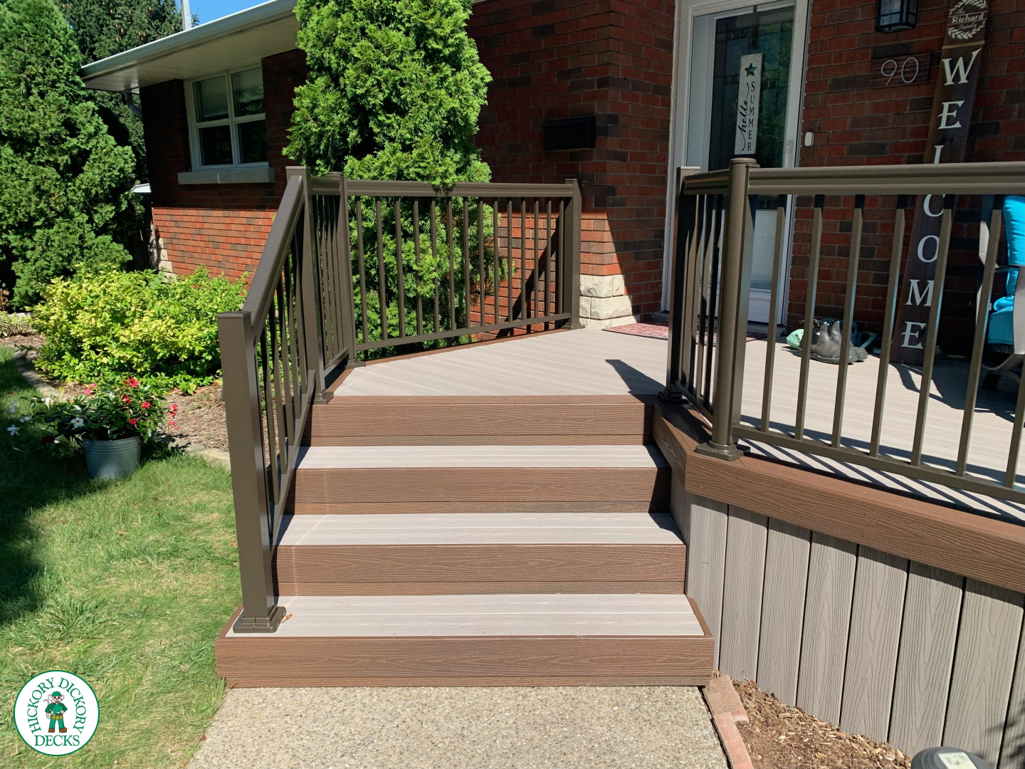 Grey front porch with brown trim and brown aluminum railing.