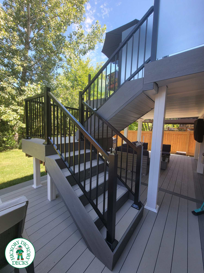 Multi level grey clubhouse deck with dark grey border and glass privacy screens on the top level.