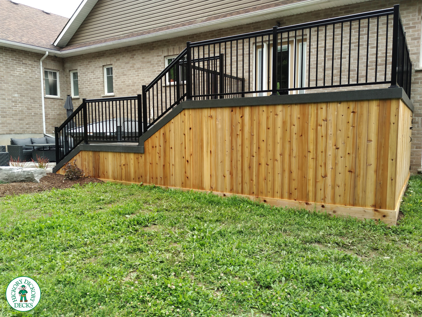 2 level clubhouse deck with cedar skirting, black aluminum railing, and grey color with darker grey border.