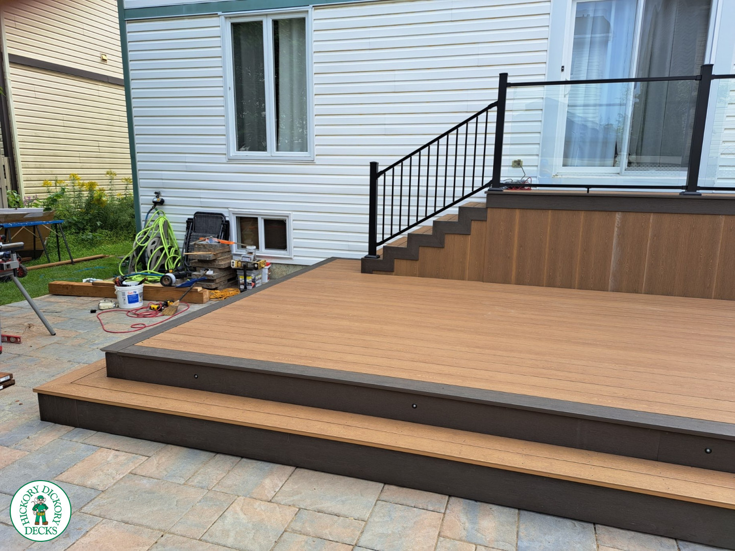 Multi level brown deck with glass railing, and a dark brown border.