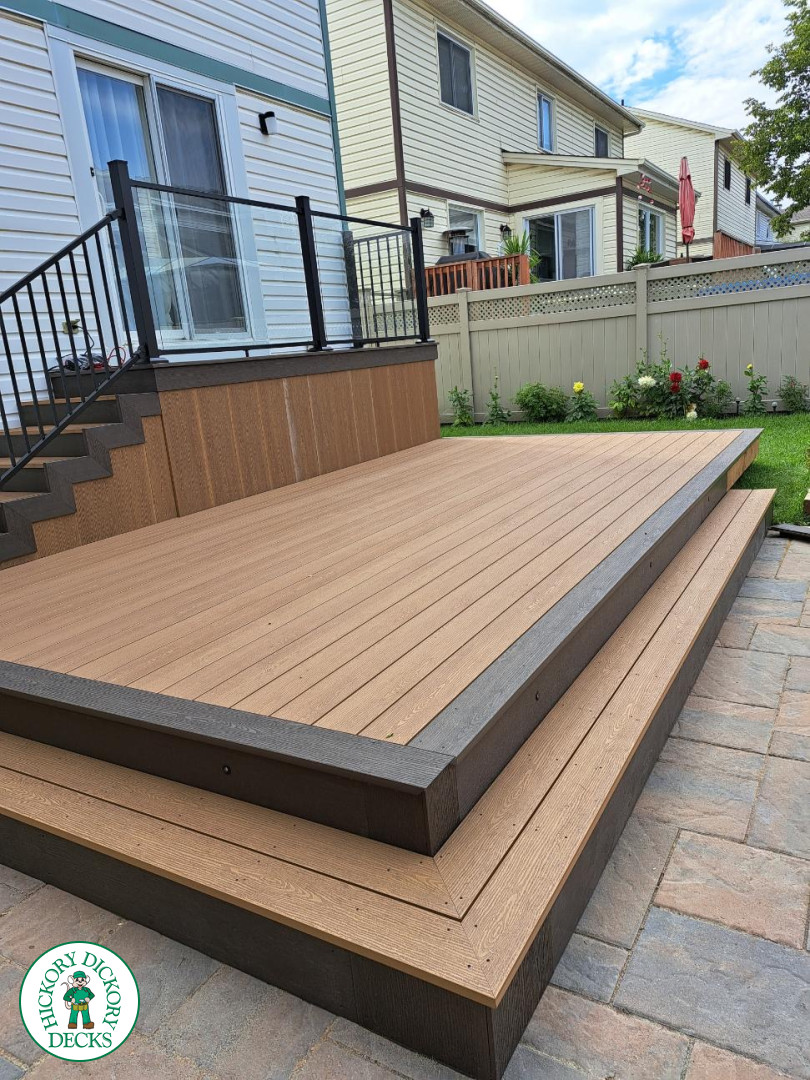 Multi level brown deck with glass railing, and a dark brown border.