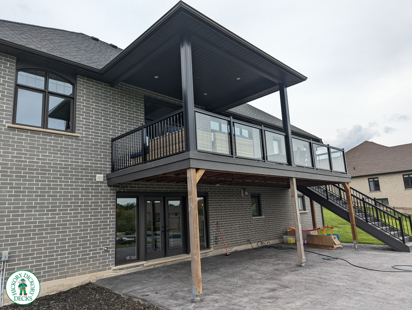 Large high grey trunorth deck with glass railings, and a custom roof structure.