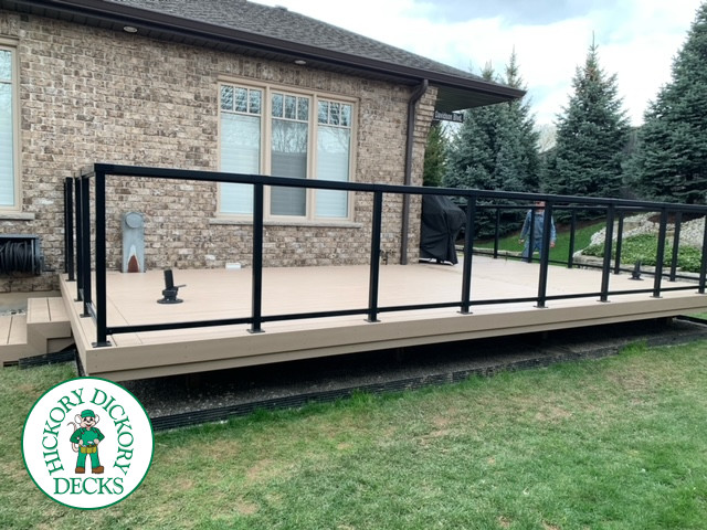 400 square foot beige composite deck with glass railings.