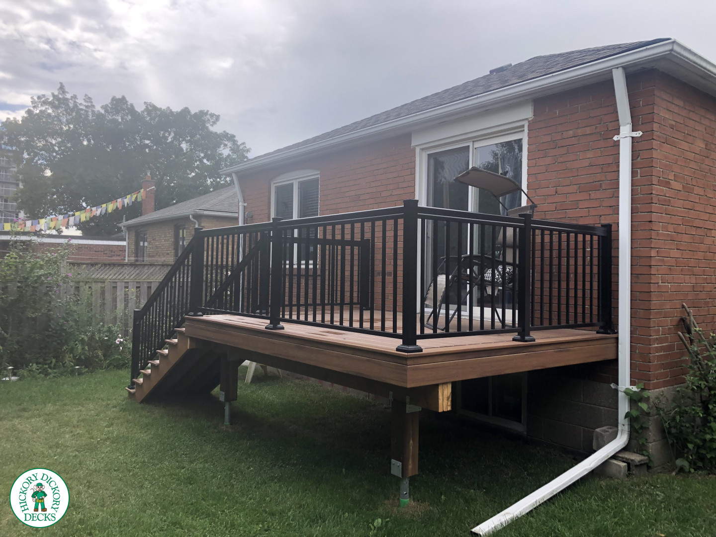 Small brown composite deck with 8 steps up and black aluminum railing.