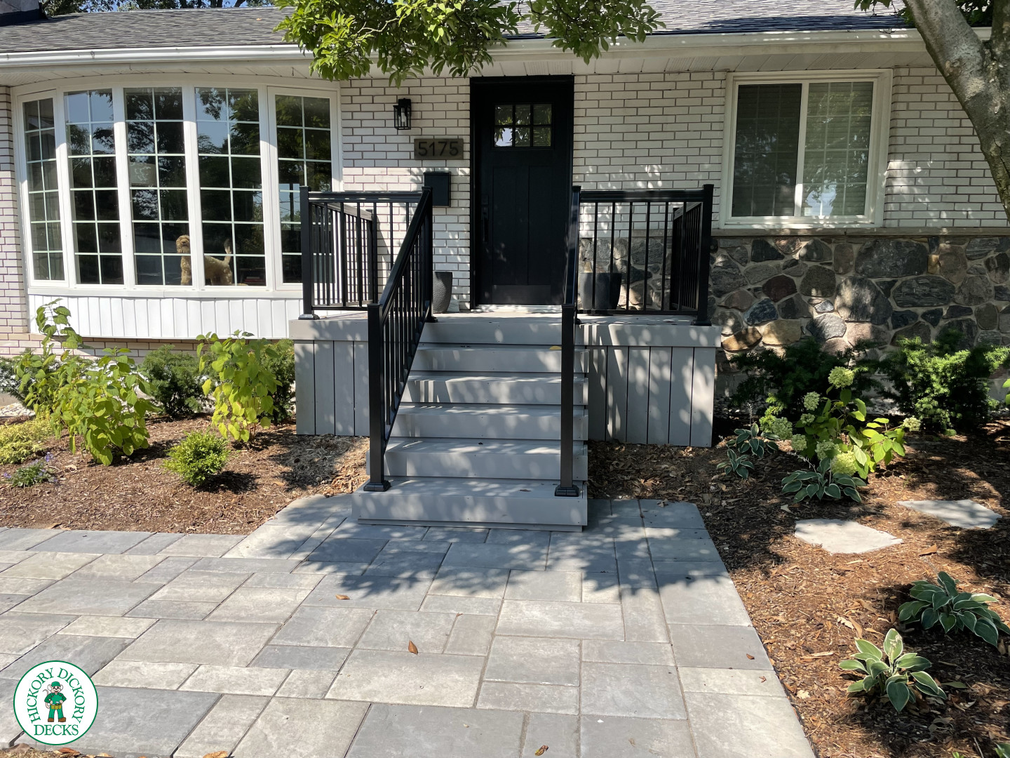 Small grey front porch with steps and black aluminum railing.