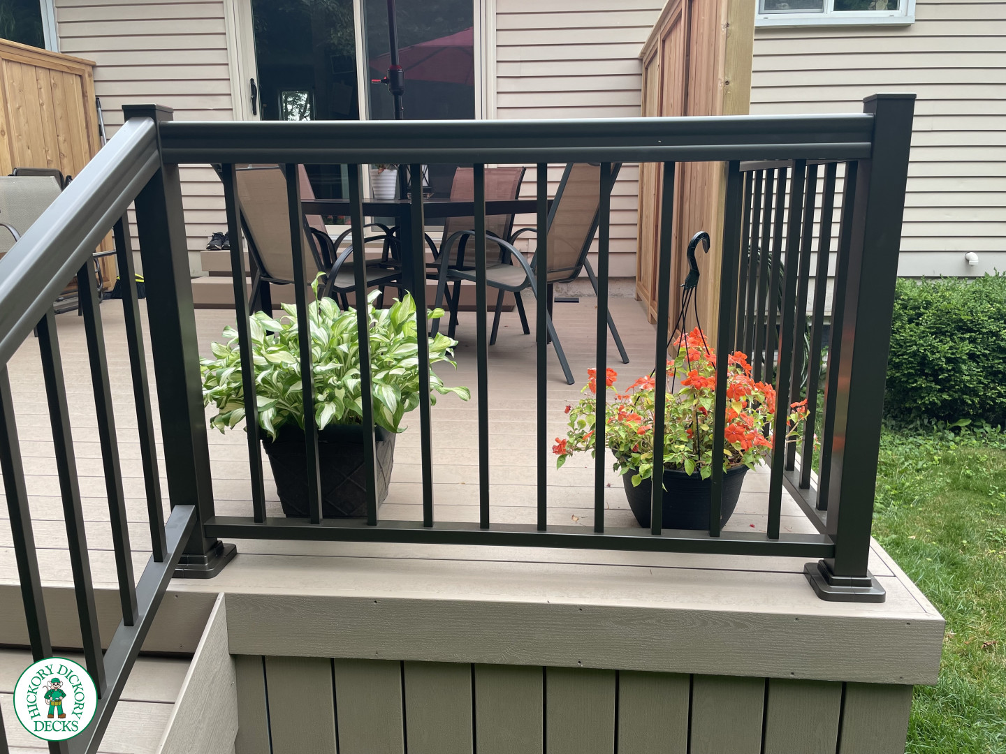 Small CLubhouse deck with four steps leading to backyard, black aluminum railing, and a cedar privacy screen.