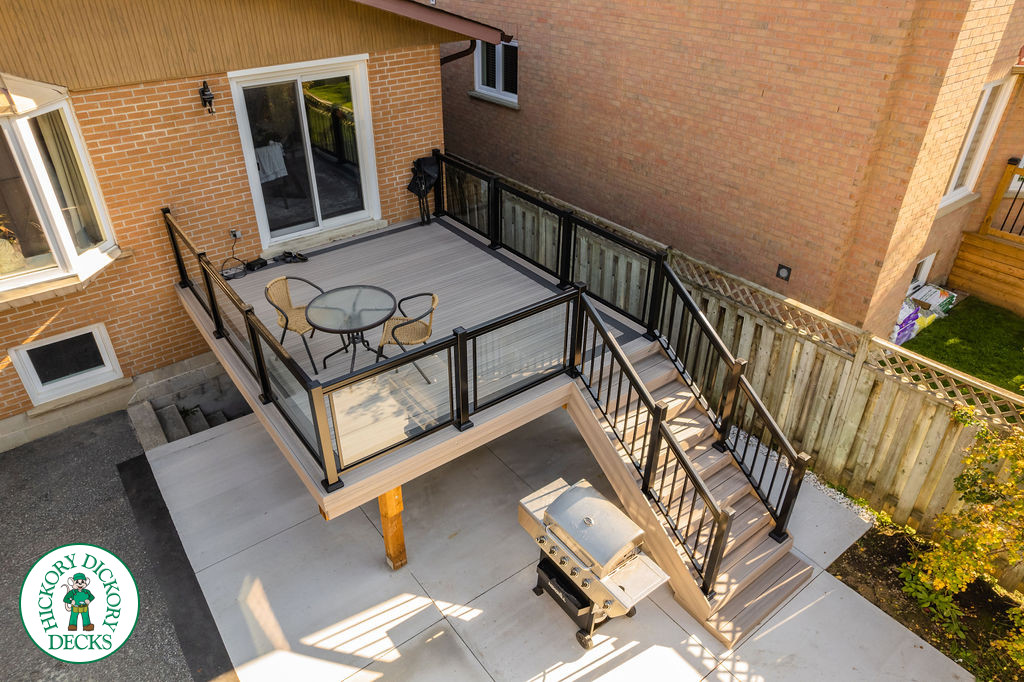 Mid rise grey composite deck with glass railings and a dark grey border.