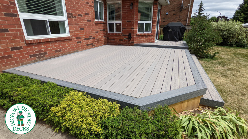 Grey composite deck with dark grey border, cedar skirt, and aluminum picket railing.