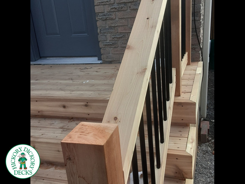 Small cedar porch with stairs and cedar railing.